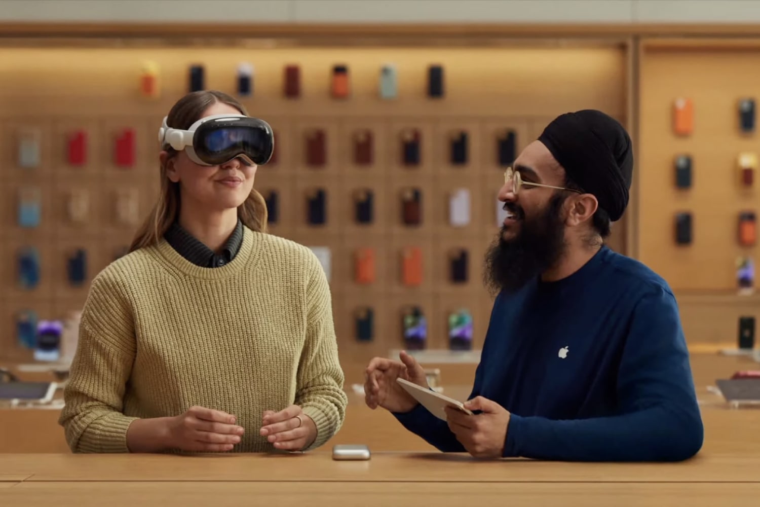 یکی از کارمندان اپل نحوه استفاده از هدست ویژن پرو را در فروشگاه اپل به شخص نشان می دهد.