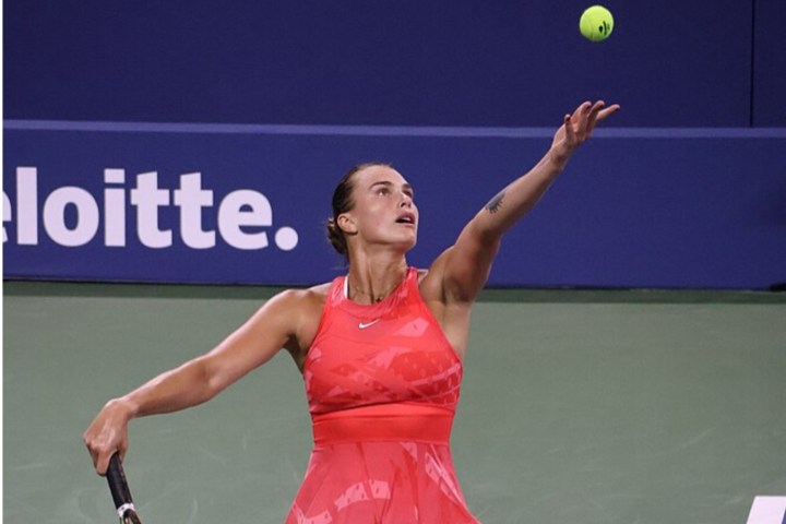 لاعبة تنس ترمي كرة تنس في الهواء.