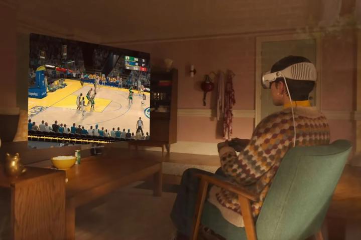 Une personne joue à un match de basket-ball à l’aide d’un casque Apple Vision Pro et d’une manette de jeux.