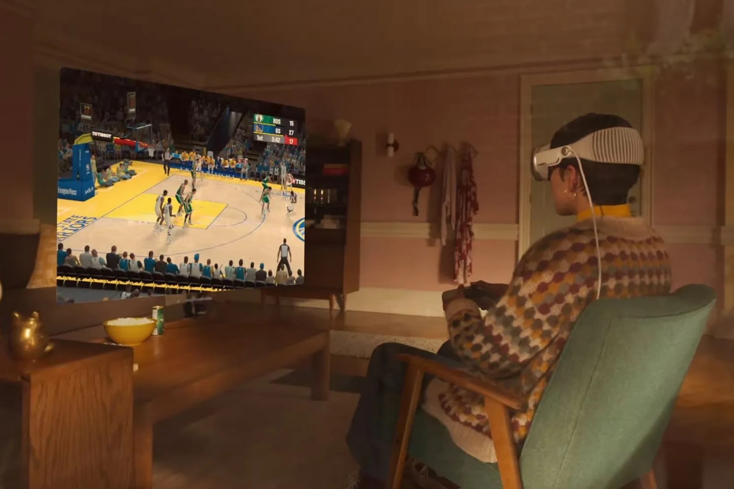A person plays a basketball game using an Apple Vision Pro headset and a games controller.