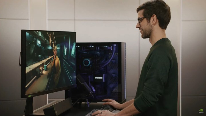 مردی مقابل یک کامپیوتر بازی ایستاده است.