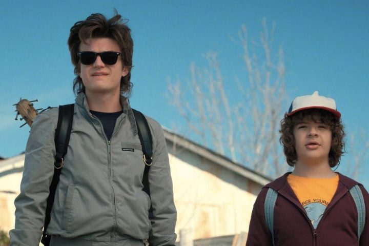 Steve and Dustin stand next to each other and stare in Stranger Things.
