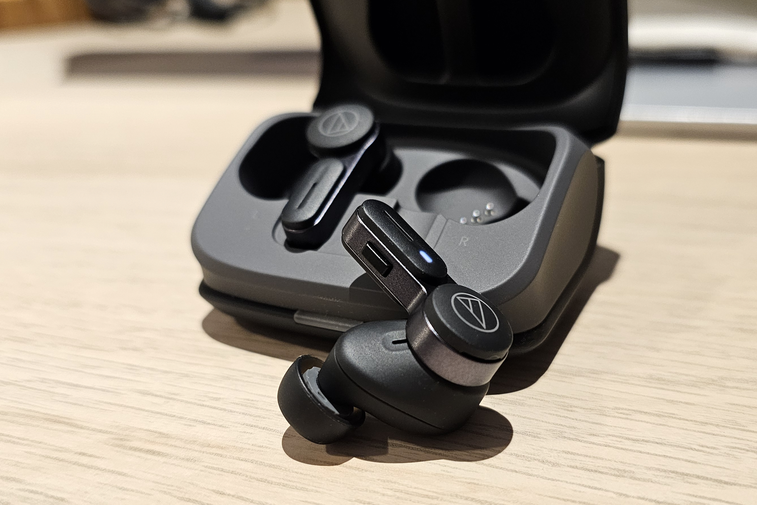 Audio-Technica ATH-TWX7 right earbud in front of case.