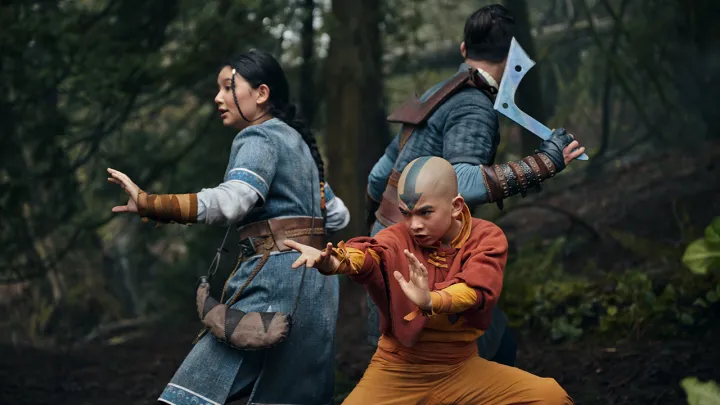 Tres personas, incluido un niño pequeño, se preparan para pelear en una escena de Avatar: The Last Airbender en Netflix.