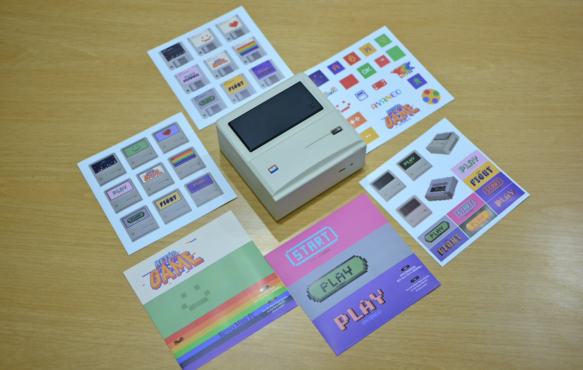 The Ayaneo Retro Mini PC AM01 with all the bundled stickers placed on a desk.