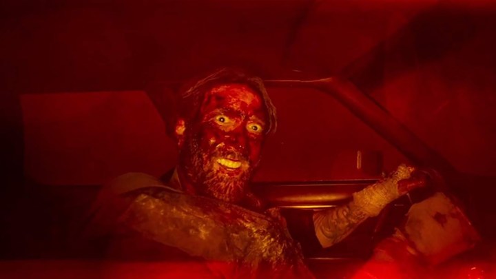 A bloody Nicolas Cage smiles in a car in Mandy.