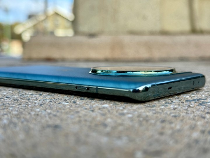 OnePlus 12 Flowy Emerald à plat sur la surface montrant une vue inclinée du curseur d'alerte et du bord supérieur plat.