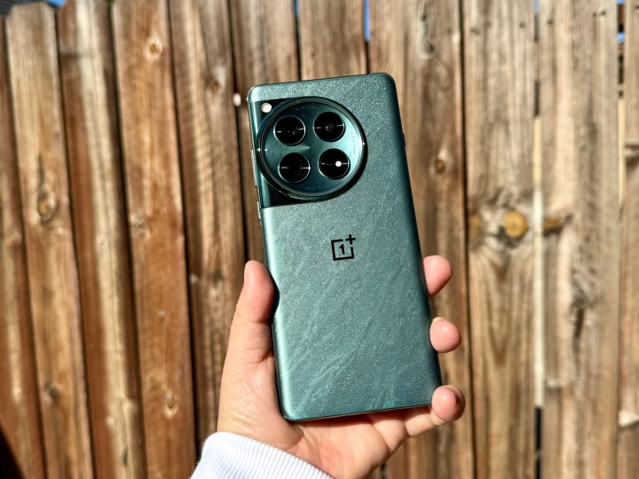 OnePlus 12 در رنگ زمردی روان در زیر نور خورشید در دست گرفته شده و درخشندگی را نشان می دهد.