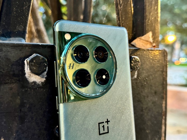 OnePlus 12 Flowy Emerald apoyado contra el poste que muestra un primer plano del módulo de la cámara.