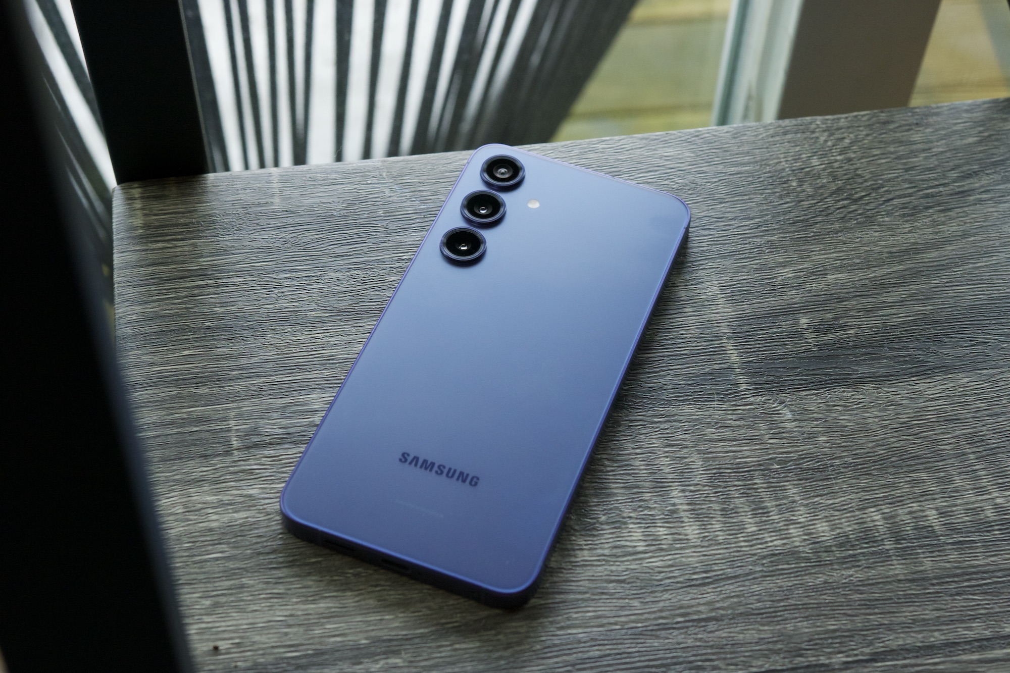 A violet Samsung Galaxy S24 Plus lying face-down on a shelf.