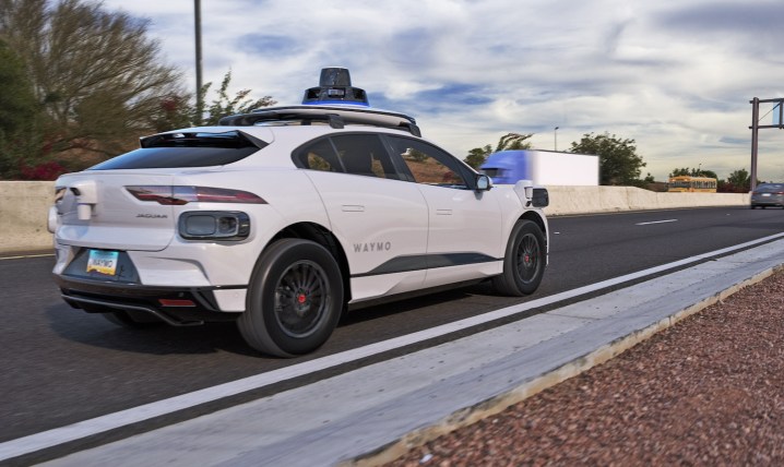 A driverless Waymo car drives along a freeway.