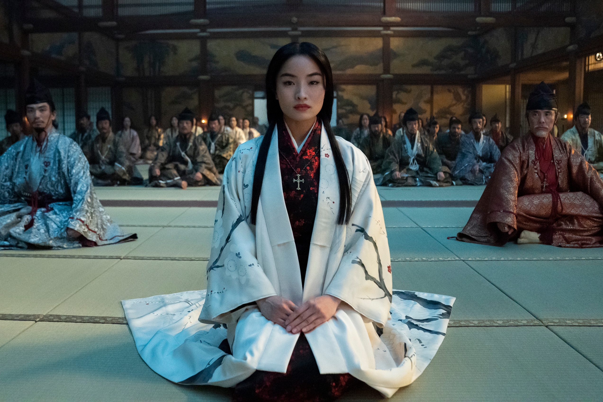 Anna Sawai kneels in a crowded room in Shōgun.