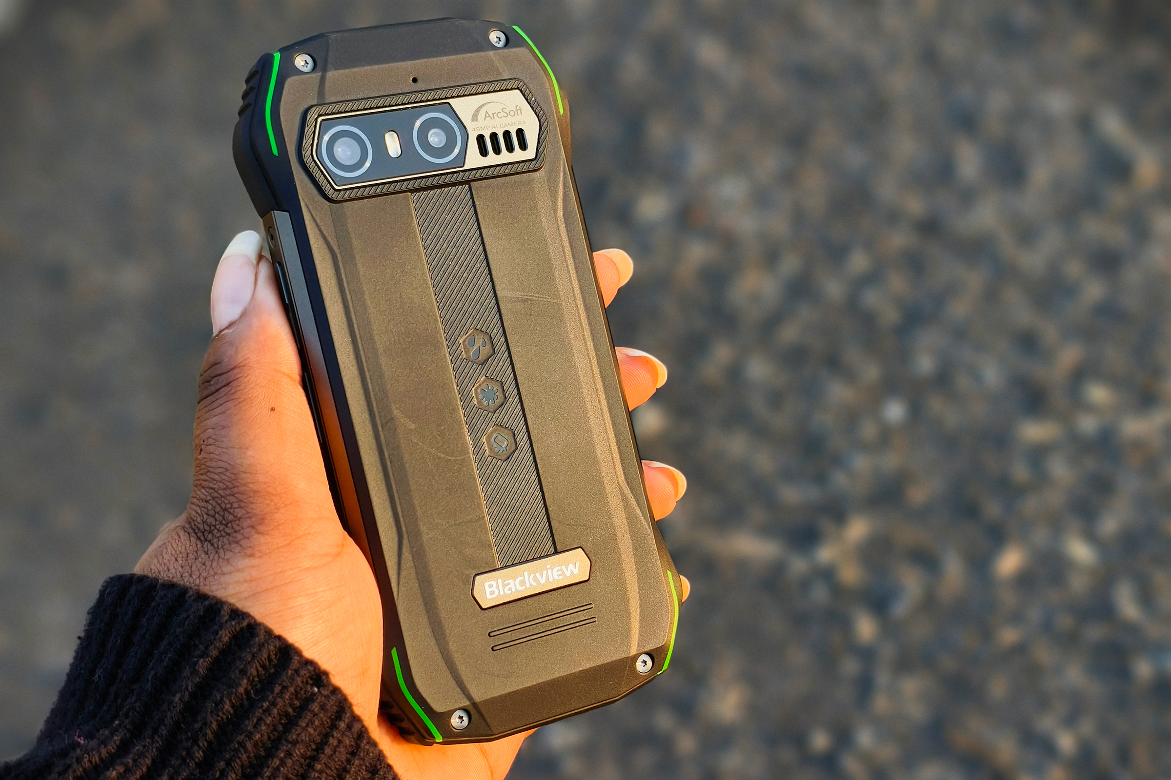 Person holding Blacview N6000 tiny rugged Android phone in hand against asphalt.