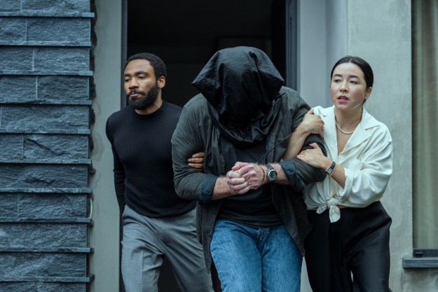Donald Glover and Maya Erskine drag a man with a bag over his head together in Mr. & Mrs. Smith.
