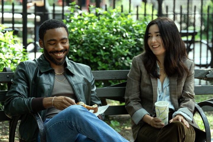 Donald Glover and Maya Erskine sit on a bench together in Mr. & Mrs. Smith.