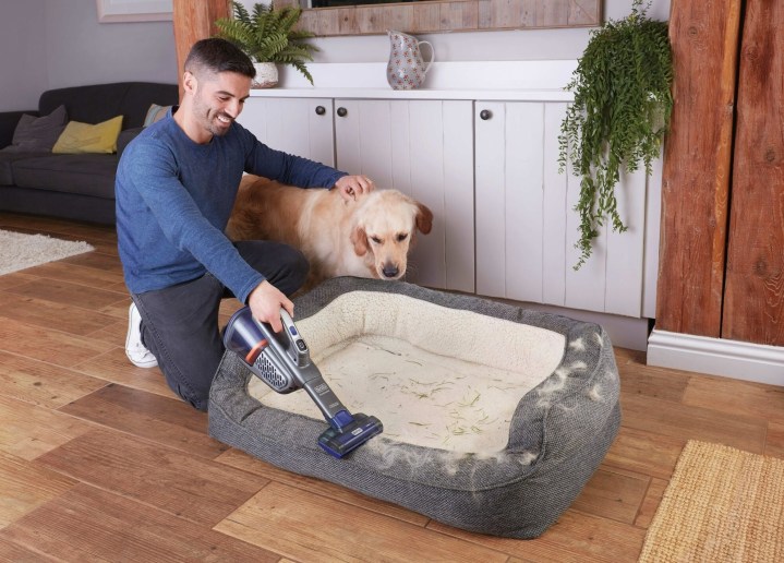 The Furbuster vacuum in use on a dog bed.