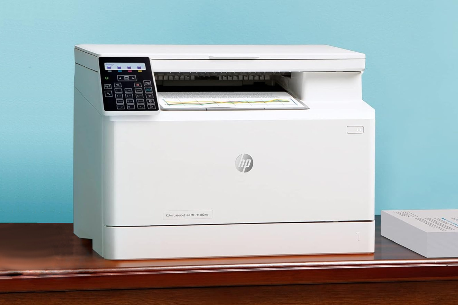 HP LaserJet Pro MFP M182nw rests beside a stack of printed documents.