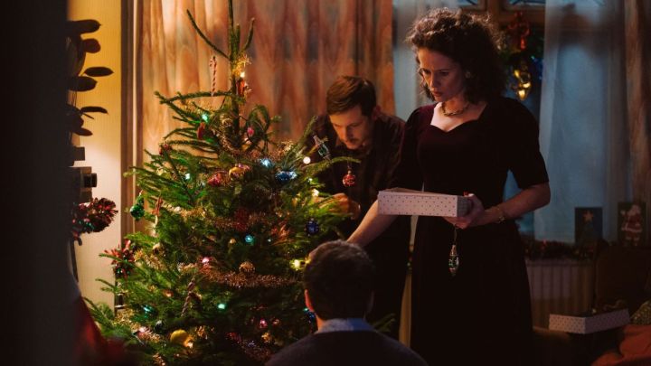 Jamie Bell y Claire Foy como el padre y la madre de Adam decorando un árbol de Navidad en la película All of Us Strangers.