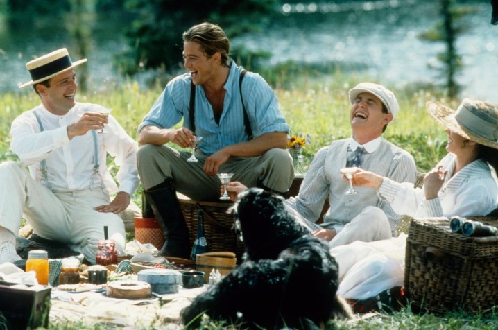 Tres hombres y una mujer se sientan y hacen un picnic.