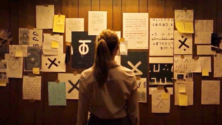A woman looks at a board full of notes in Longlegs.