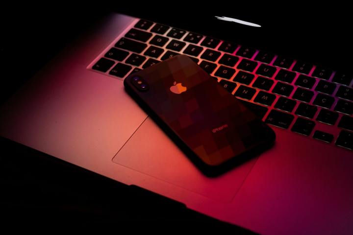 A MacBook and iPhone in dark red light.