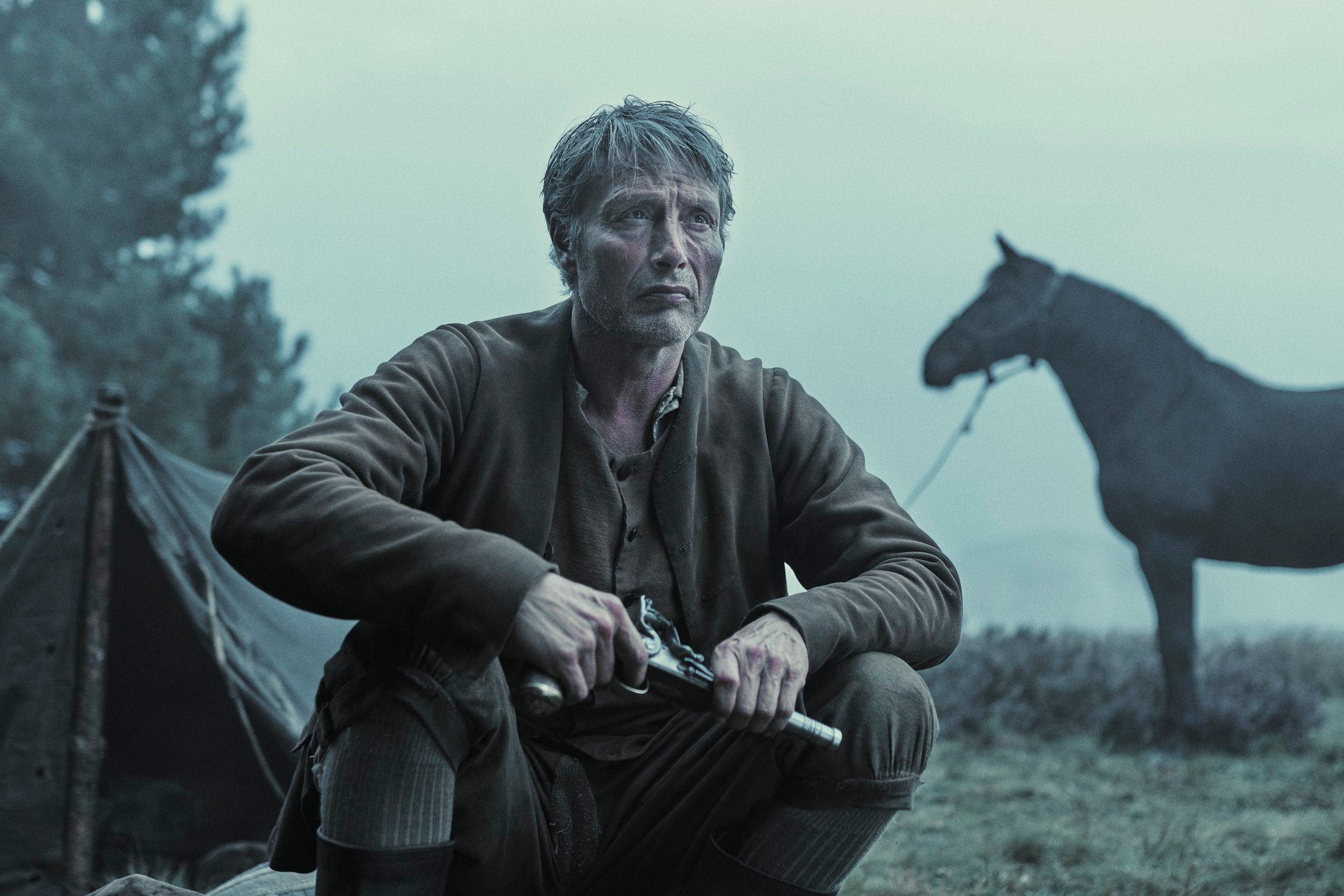 Mads Mikkelsen holds a pistol in The Promised Land.