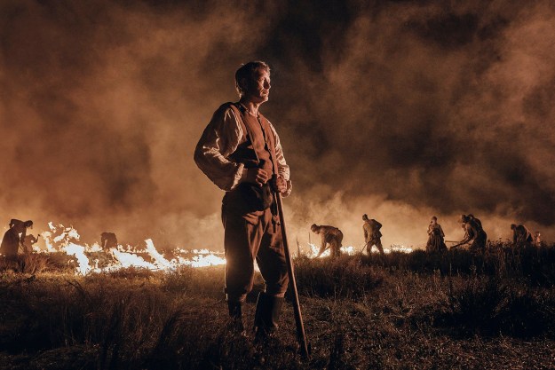 Mads Mikkelsen stands near a burning field in The Promised Land.