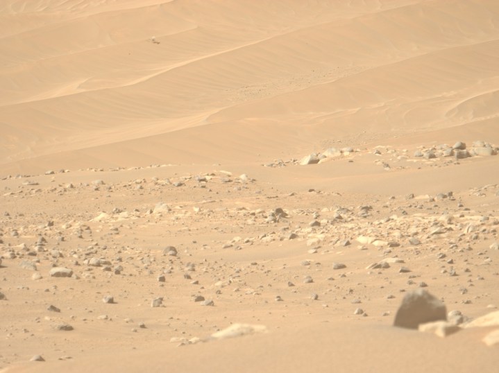 A Mars landscape with NASA's Ingenuity helicopter in the background.