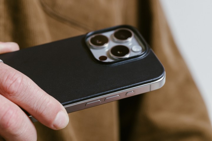 Personal holding iPhone 15 Pro with black Nomad Magnetic Leather Back attached.