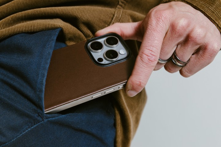 Personal taking iPhone 15 Pro out of pocket with Rustic Brown Nomad Magnetic Leather Back attached.