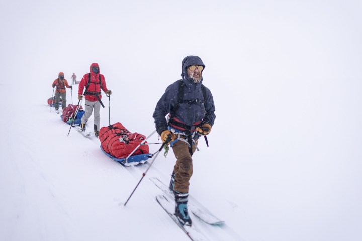 Экспедиционная группа идет по снегу, тянущая сани.