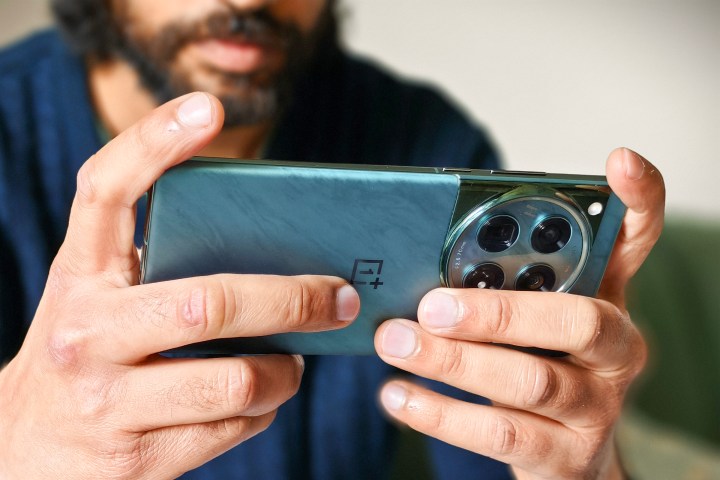 Person holding green OnePlus 12 phone in hands while playing games.