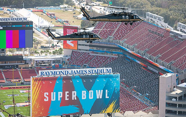 Helicopters fly over the Super Bowl stadium.