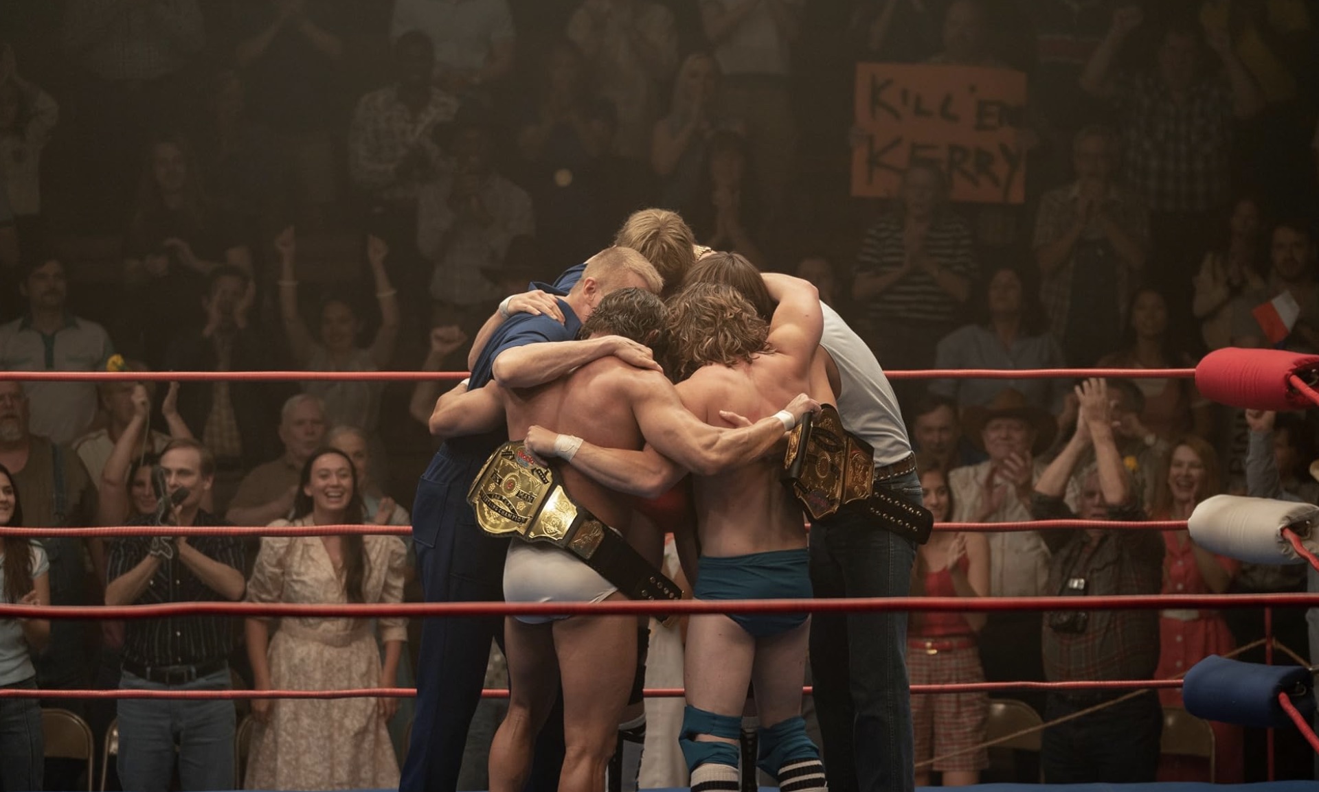 Bir grup adam güreş ringinin ortasında sarılıyor.