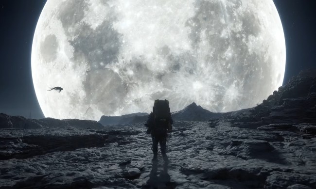 Sam Bridges walks on a ridge in front of the moon.