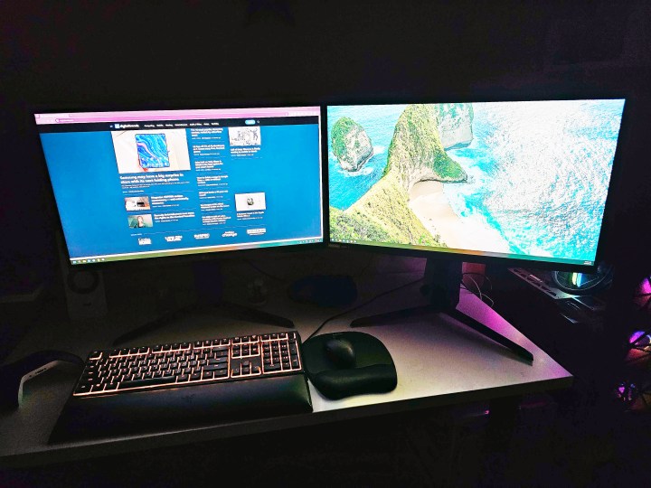 Two LG UltraGear monitors sit on a desk in front of a dark background.