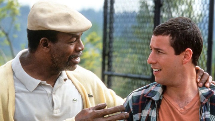 Carl Weathers as Chubbs with his arm around Adam Sandler as Happy Gilmore, the two men looking at one another in a scene from Happy Gilmore.