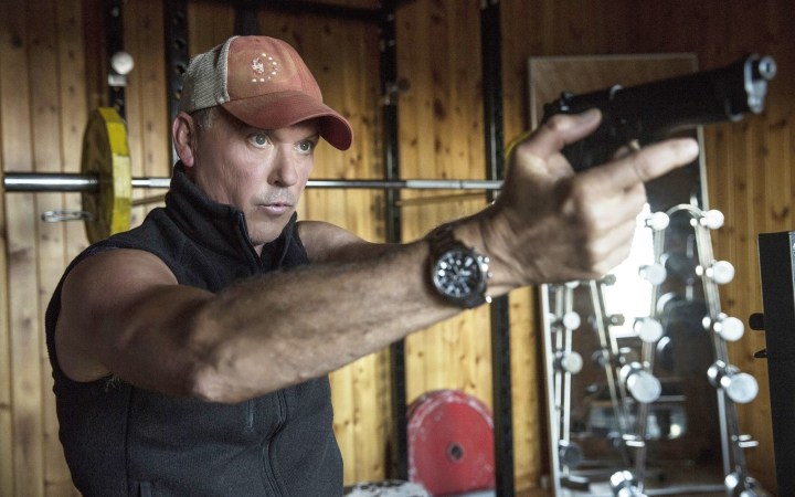 Michael Keaton points a gun in American Assassin.