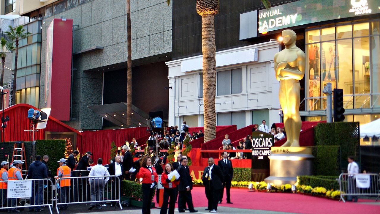 The outside of the Oscars showing people milling about and the red carpet.