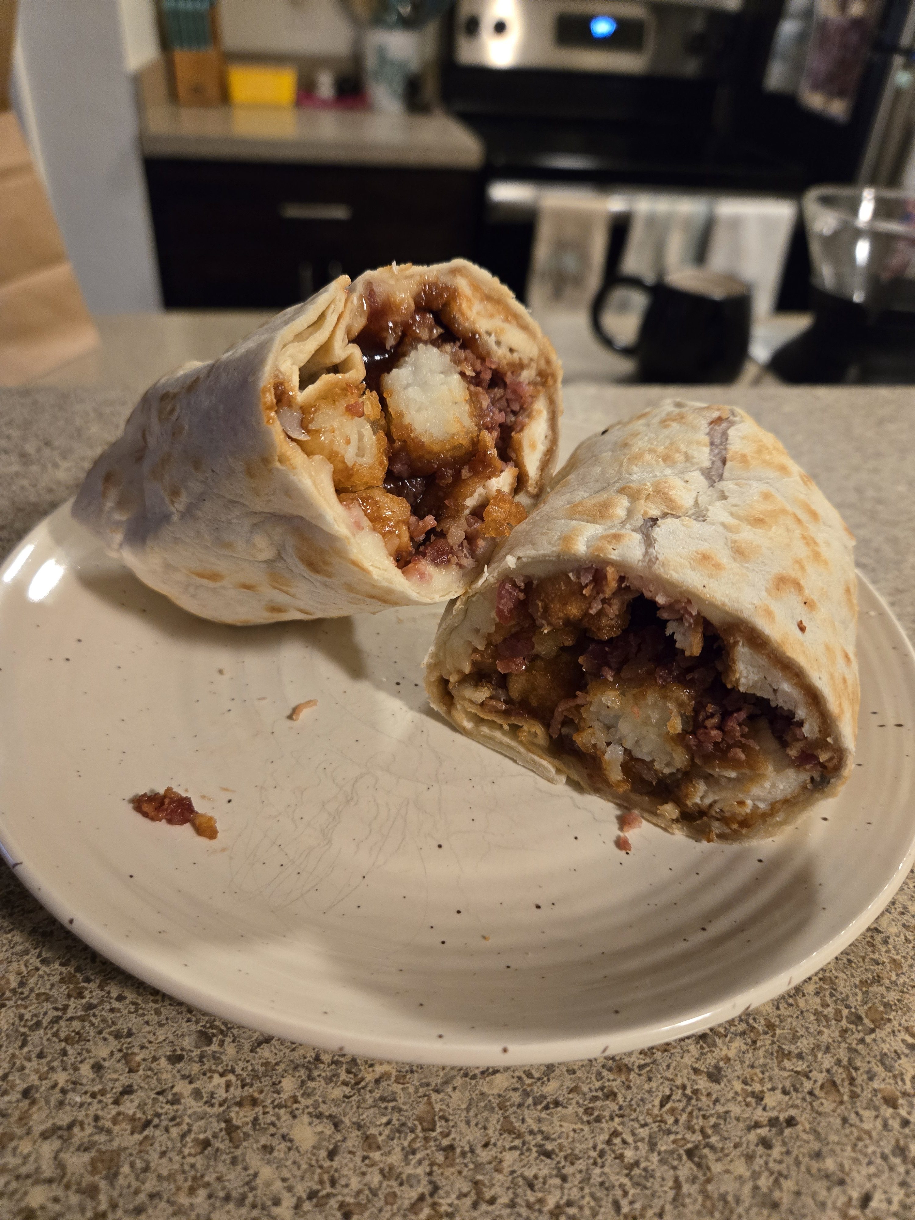 A photo of a wrap with tater tots and chicken tenders.
