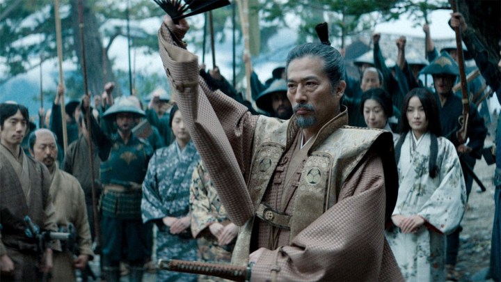 A samurai drawing in a sword, a crowd behind him in a scene from Shogun on Hulu.
