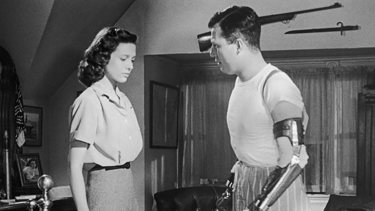 A black and white image of Harold Russell in a scene from The Best Years of Our Lives standing beside a woman.