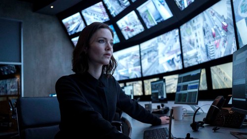 A woman looks at a wall of TV screens in The Capture.