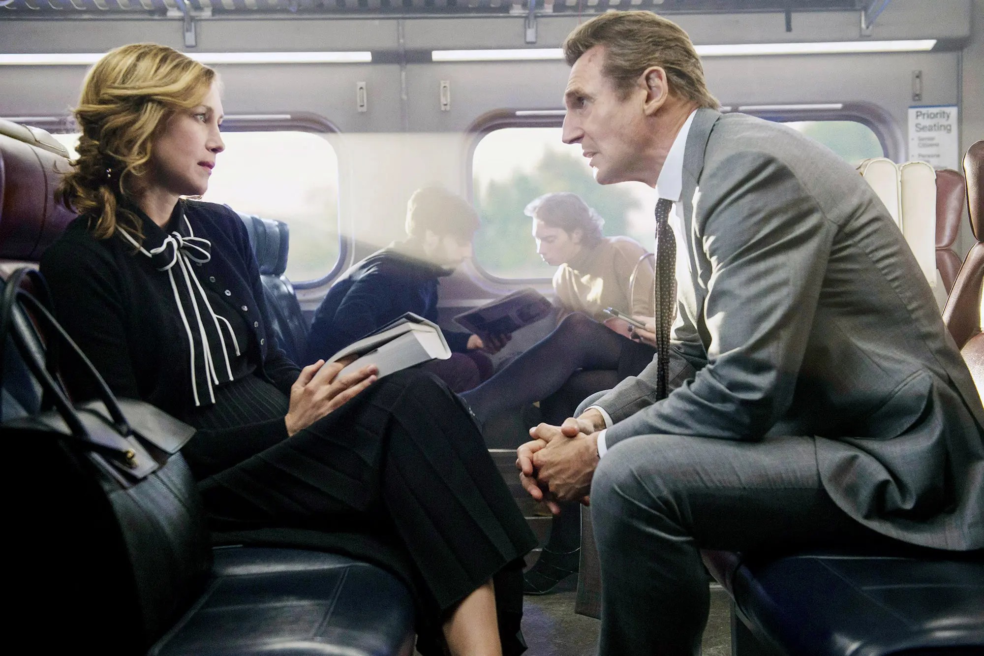A man and a woman sit on a train in The Commuter.