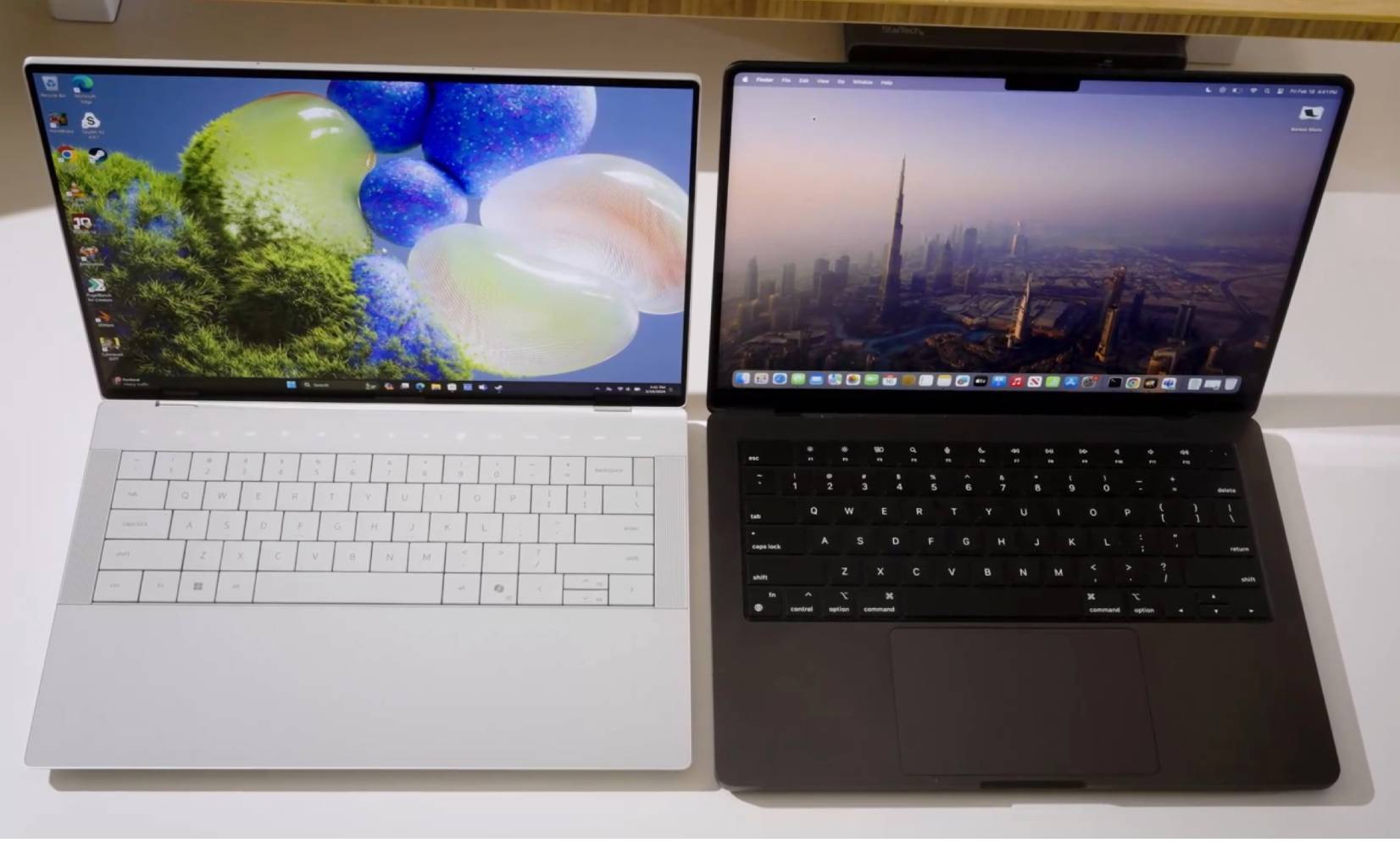 Dell XPS 14 এবং MacBook Pro একটি সাদা ডেস্কে পাশাপাশি।