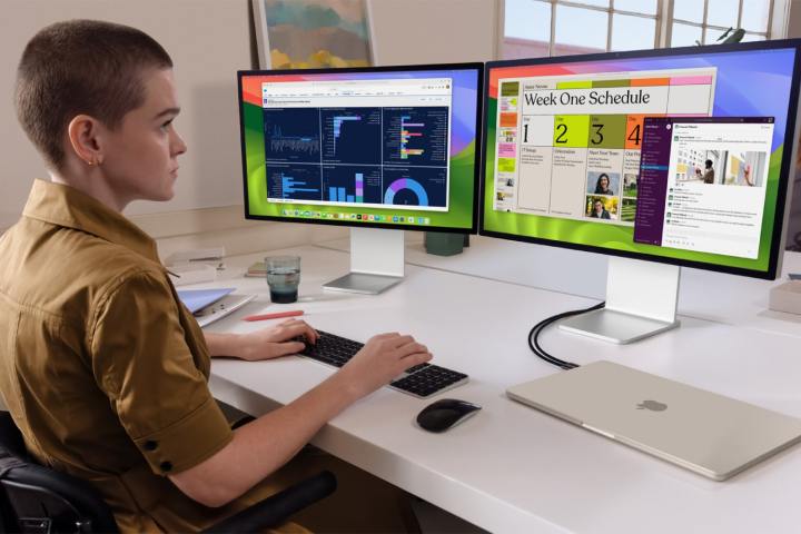A person using a MacBook Air connected to two monitors.