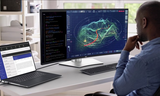 A person using the Dell UltraSharp 40 U4025QW 40-inch curved Thunderbolt hub monitor with a Dell laptop on a desk.