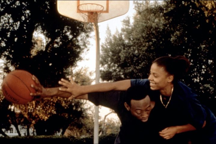 Un chico sostiene una pelota lejos de una chica en la cancha de baloncesto.