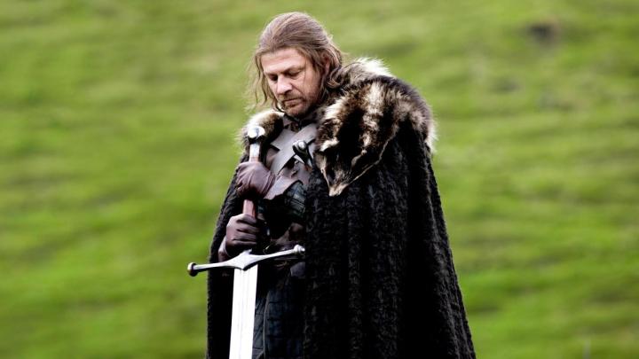 Sean Bean as Ned Stark holding the Valyrian steel sword Ice in an open field in Game of Thrones.