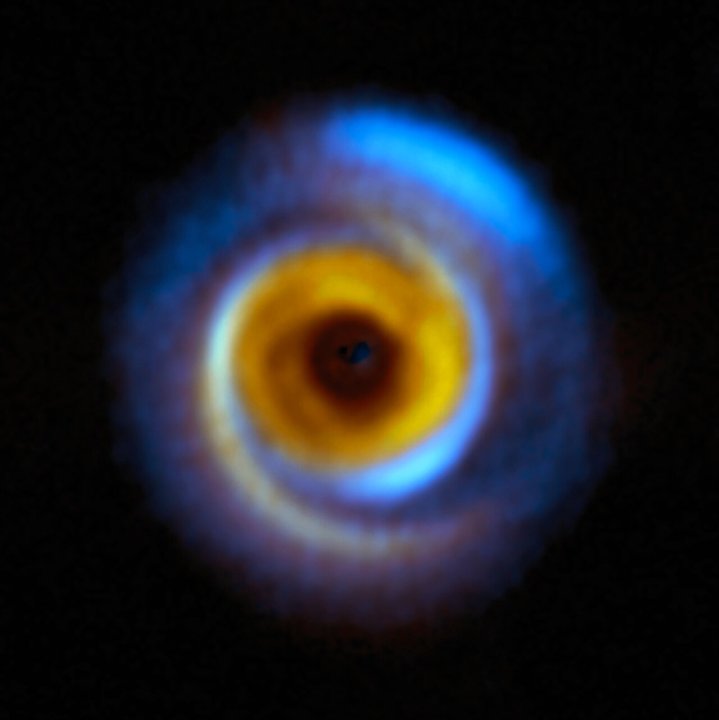 Esta imagen compuesta muestra el disco de formación planetaria MWC 758, ubicado a unos 500 años luz de distancia en la región de Tauro, visto con dos instalaciones diferentes. El color amarillo representa las observaciones infrarrojas obtenidas con el instrumento Spectro-Polarimetric High-contrast Exoplanet REsearch (SPHERE), instalado en el Very Large Telescope (VLT) de ESO. Las regiones azules, por su parte, corresponden a observaciones realizadas con el Atacama Large Millimeter/submillimeter Array (ALMA).